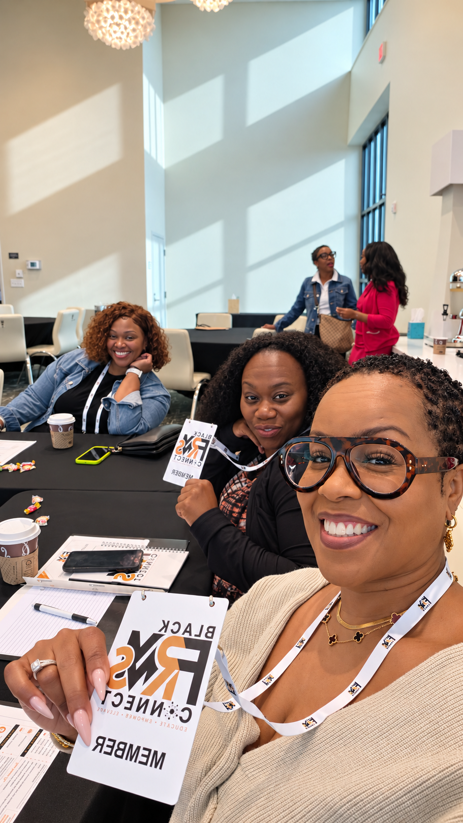 Black FRMs Connect members smiling at a conference table, holding their member badges